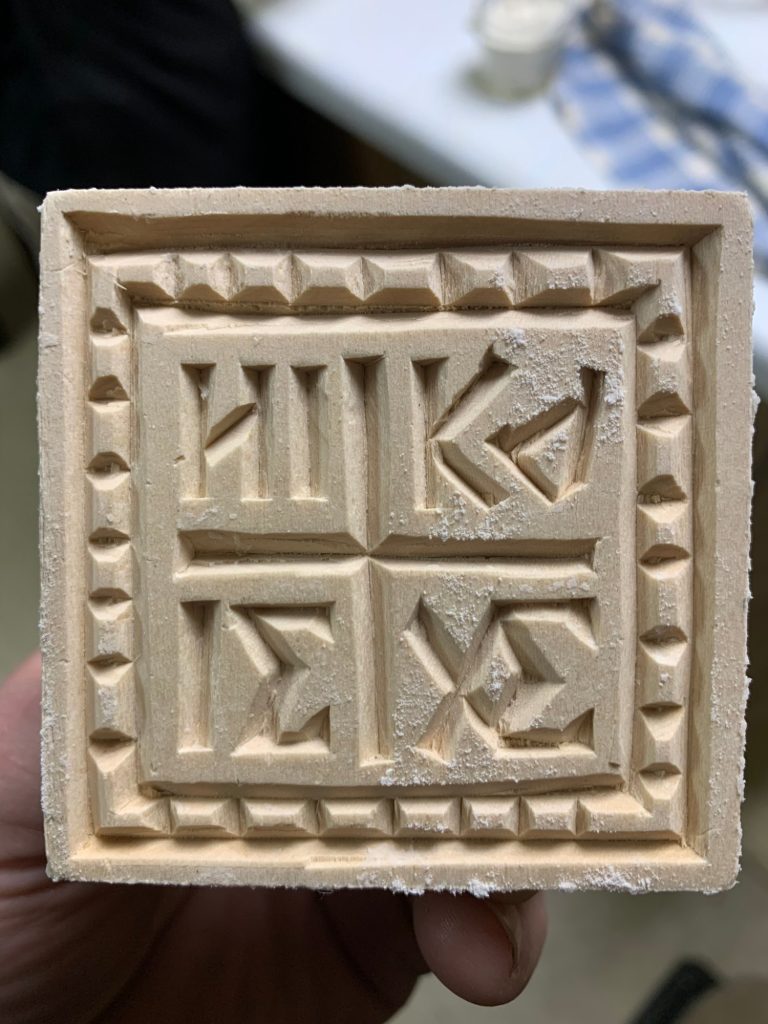 The prosphora stamp, a hand-carved wooden stamp.